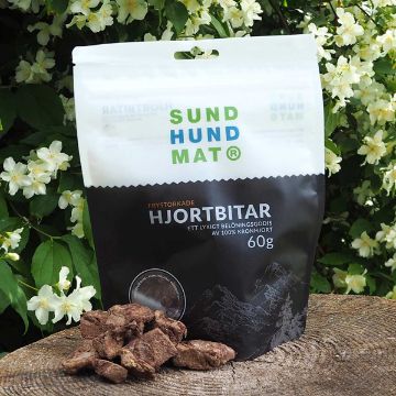Hjortbitar från Sund Hundmat - ett lyxigt hundgodis Frystorkade hjortbitar från Sund hundmat kommer i en praktisk återförslutningsbar påse. Hjortbitarna är lite oregelbunda  i sin form. Påsen är mörkbrun och vit.
