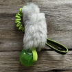 Hälge är en hundleksak med grön boll och grönt expanderhandtag. Vitt svenskt fårskinn.